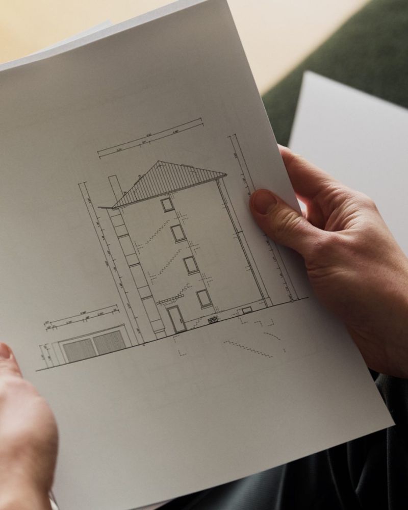 Hände halten den Aufriss eines Hauses
